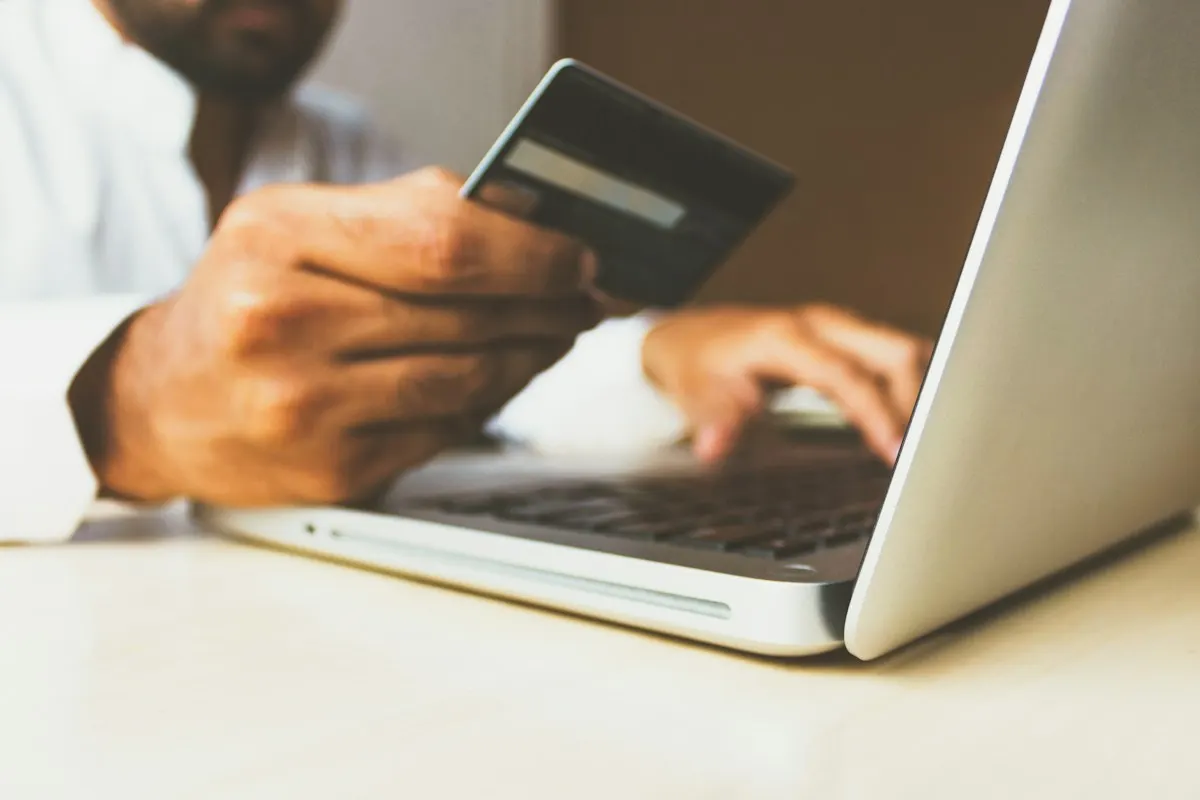 Person holding a credit card while shopping on a laptop