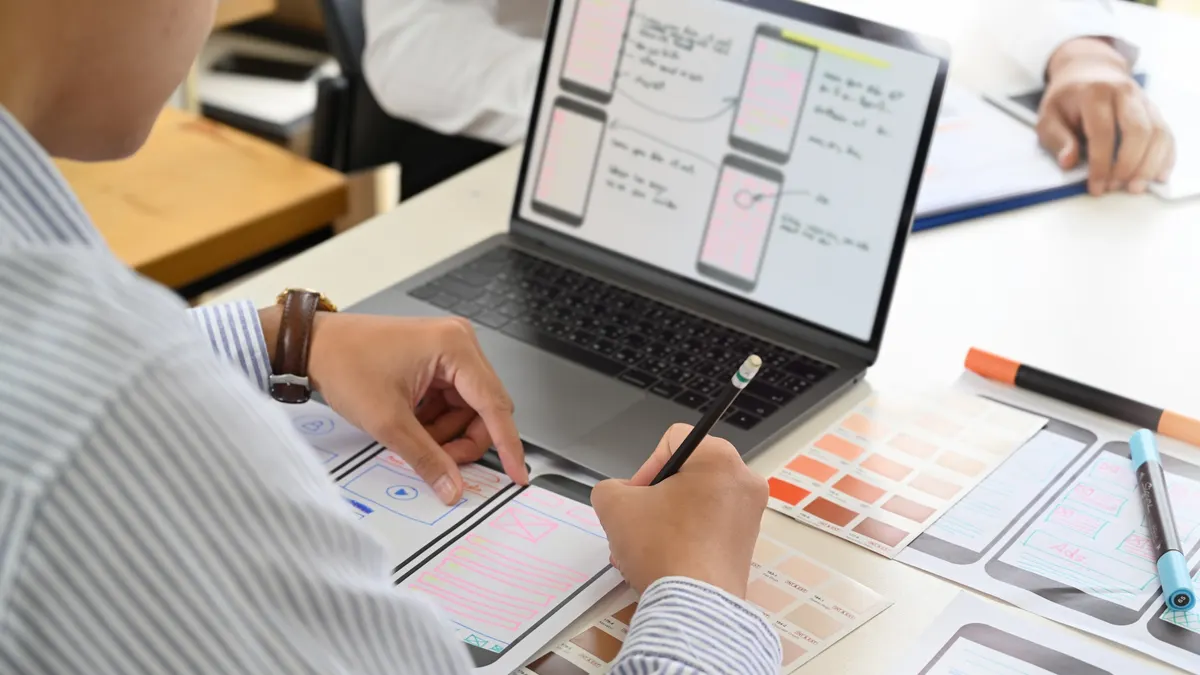 A person is sketching a design for a mobile website or app