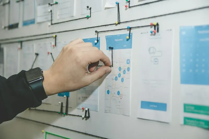 Hand arranging a customer journey map on a wall